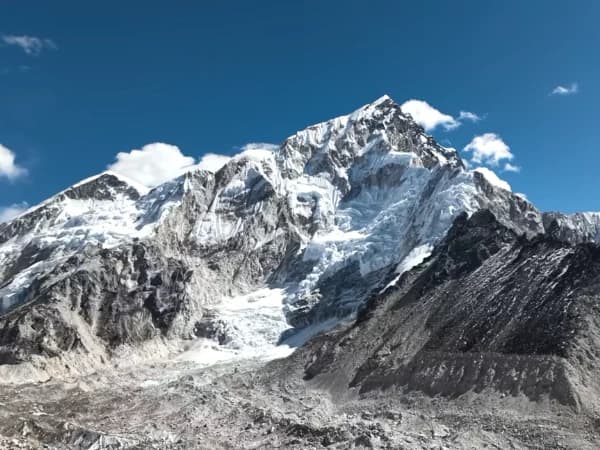 Trekker walking toward Everest Base Camp with snow-capped Himalayan peaks under clear November blue skies