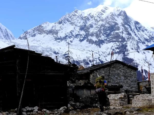 Manaslu Circuit trek view of snowy mountain peaks rising above a traditional Himalayan village
